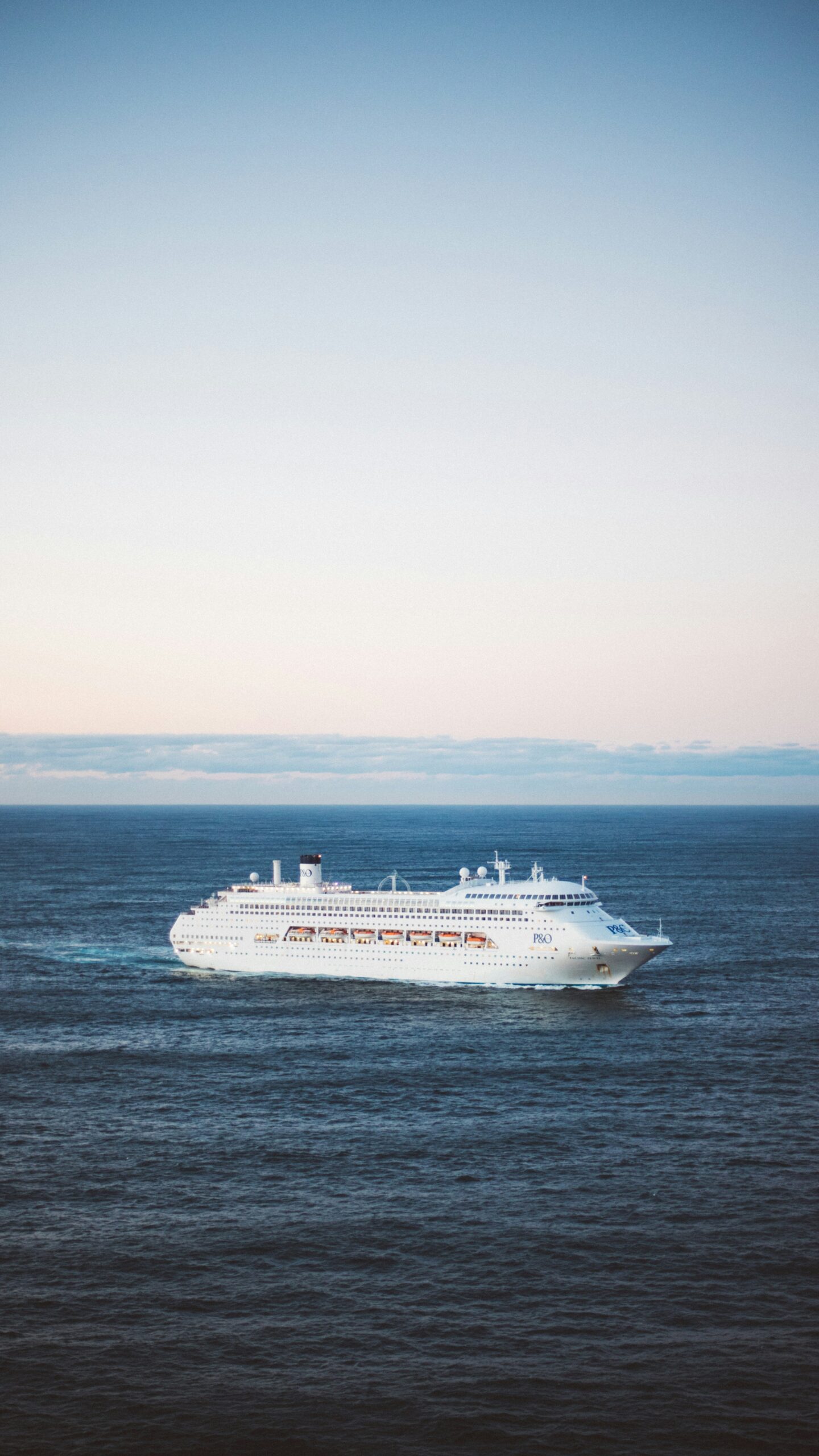 A mid-size cruise ship seen from a distance at dusk