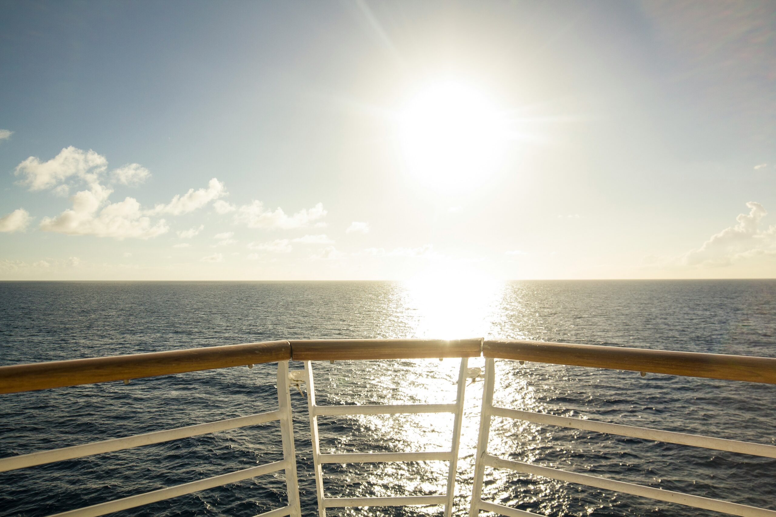 Standing at the deck railing watching the sunrise over open water
